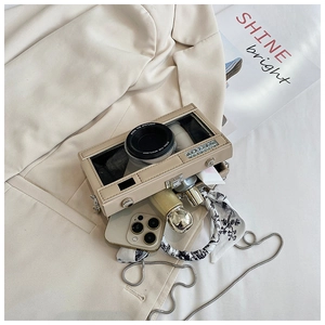 Internal view showing capacity of the beige camera shaped crossbody bag with accessories