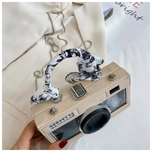 Detail of a vintage camera-shaped beige bag with silk scarf handle and metal chain