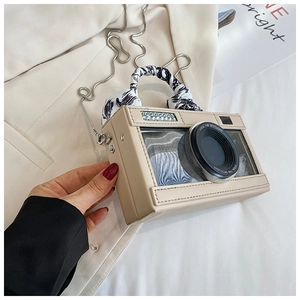 Detail of creative camera bag with decorative lens, silk scarf handle and silver chain strap