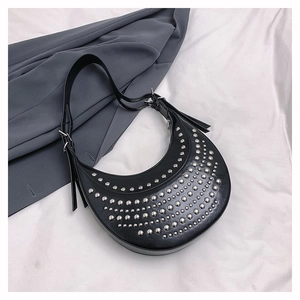 Détail du sac croissant noir avec rivets punk argentés sur tissu blanc souple