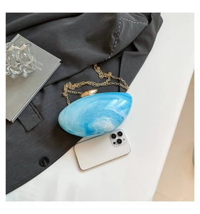 Close-up of marble pattern acrylic clutch with gold hardware and fine chain strap
