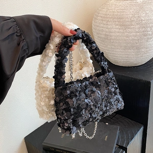 Chic sequin handbags in black and white with metal chains shown from a front angle