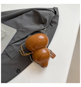 Dettaglio borsa in pelle marrone a forma di zucca con catena argento su una giacca