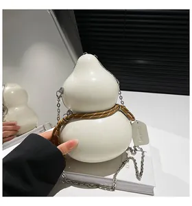 Dettaglio borsa a tracolla color crema a forma di zucca con catena in metallo e corda