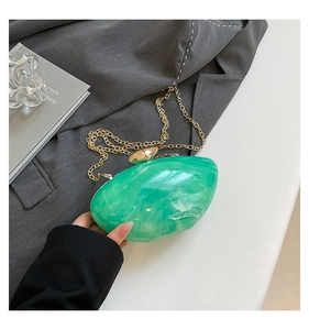 Detailed close-up of emerald marble acrylic clutch bag with golden bean buckle and chain