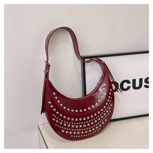 Détail du sac croissant bordeaux avec rivets punk argentés sur cuir synthétique brillant