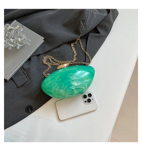 Detail of emerald marble acrylic clutch bag showing scale with a smartphone