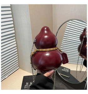 Dettaglio borsa a zucca rosso vino in pelle lucida con corda dorata e catenella