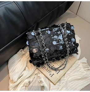 Détail du sac à paillettes noires avec bandoulière chaîne sur un livre d'art
