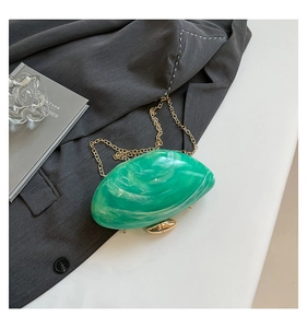 Detail of green marble acrylic clutch bag with gold chain strap on grey suit background