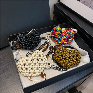 Handmade heart-shaped beaded mini bags in various colors with woven shoulder straps