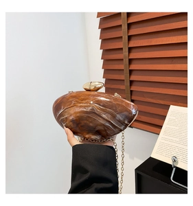 Detailed shot of amber marble acrylic clutch with gold chain strap in a lifestyle setting