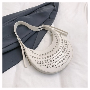 Close-up of white crescent shoulder bag with silver rivet studs and metal buckle detail