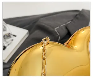 Detailed macro view of glossy golden lobster clasp and metallic chain on heart acrylic bag