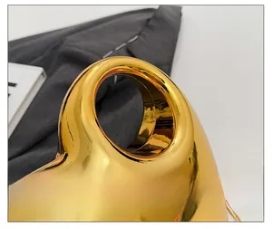 Detailed close-up of shiny gold heart-shaped acrylic handbag with metallic mirror finish