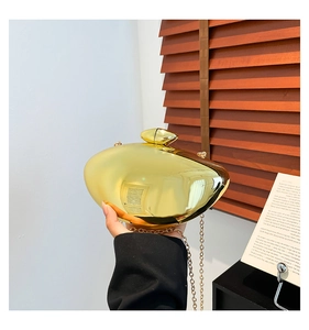 Detail of mirror-finish gold metal clutch bag with slim chain and elegant clasp