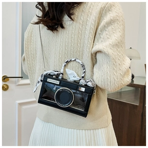 Detail of camera-shaped bag with pearl trim and stylish scarf handle on a model