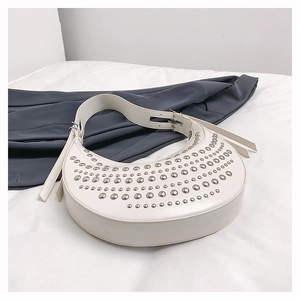 Detail of white half-moon bag featuring silver metal studs and smooth leather texture