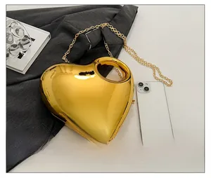 Macro view of gold heart acrylic clutch bag showing compact size compared to a phone