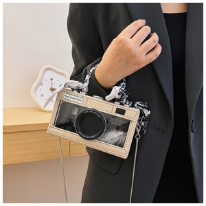 Detail of creative camera-shaped bag with PVC window, rhinestone decor and silk scarf handle