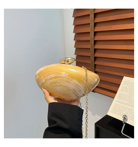 Macro detail of amber yellow marble acrylic clutch bag with a golden metal chain