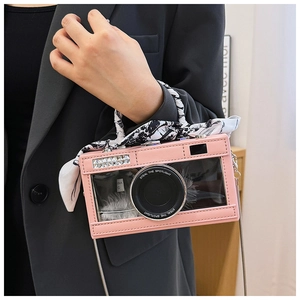 Detail of pink camera-shaped crossbody bag with transparent window and feather decor