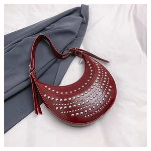 Detail of dark red crescent bag with silver punk rivets and adjustable buckle strap