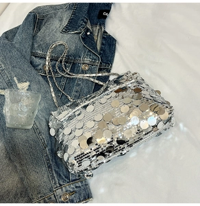 Gros plan d'un sac bandoulière argenté à paillettes avec chaîne sur un fond en jean mode
