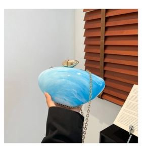 Detailed close-up of blue marble acrylic shell bag with golden clasp and chain strap