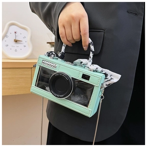 Detail of mint green camera-shaped crossbody bag with silk scarf handle and chain strap