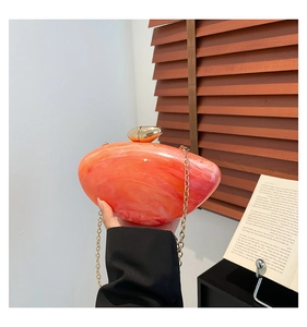 Detail of orange marble acrylic handbag with golden pebble clasp and fine chain strap