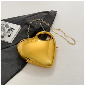 Detail of a heart-shaped gold clutch bag with metallic finish and delicate chain strap