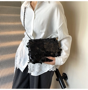 Détail d'un sac à bandoulière à paillettes noires avec bandoulière chaîne et rabat plié