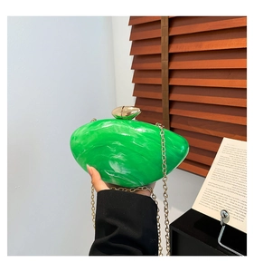 Macro detail of emerald green marble acrylic handbag with golden sphere clasp and chain