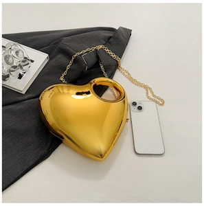 Macro detail of glossy gold heart-shaped clutch bag with metal chain and top handle