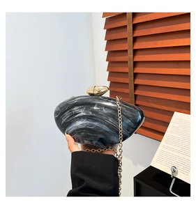 Close-up of marble pattern acrylic clutch with gold hardware and chain strap