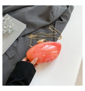 Detail of pink marble acrylic mango bag with gold chain strap on grey blazer jacket