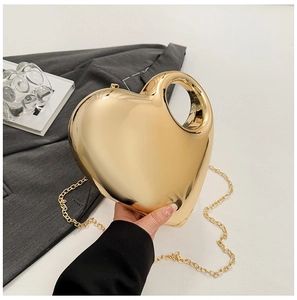 Detail view of heart-shaped gold acrylic clutch bag with metallic mirror finish and chain