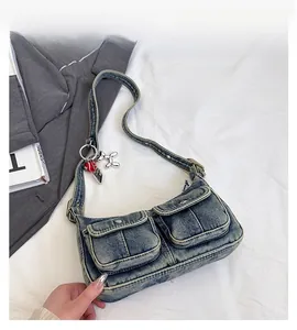 Detail of vintage washed denim underarm bag with double front pockets and cute heart charm