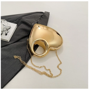 Detail of golden heart-shaped acrylic clutch with hollow handle and chain strap