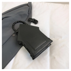 Detail of black pentagonal crossbody bag with bamboo handle and detachable strap on a blazer