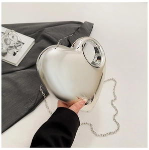 Detail of silver heart-shaped acrylic evening bag with metallic chain strap and handle