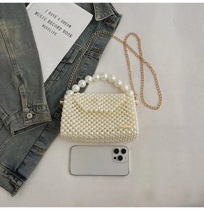 Detailed view of woven white pearl handbag with golden chain strap and logo plaque