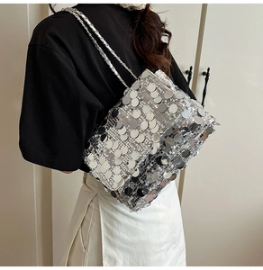 Gros plan d'un sac bandoulière argenté à paillettes avec chaîne porté par un modèle
