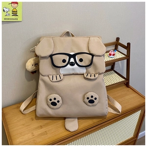 Detail of cute khaki dog backpack showing plush ears, glasses, and decorative charm