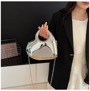 Detail of silver mirror heart bag with integrated handle and thin metal chain strap