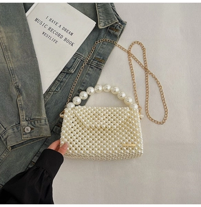 Detail of a handmade white pearl beaded handbag with a golden chain on denim background