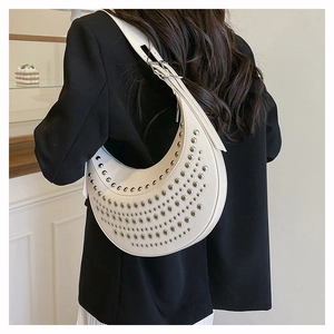 Vue détaillée d'un sac à bandoulière blanc en demi-lune avec des rangées de rivets