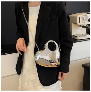 Silver mirror heart-shaped crossbody bag with slim chain strap on a model shoulder