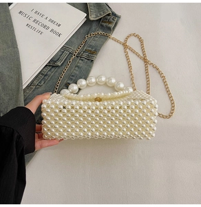 Detail of white pearl woven handbag with gold chain strap and rounded pearl handle